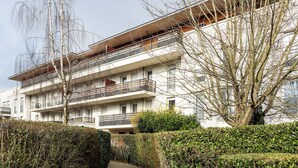 A multi-story residential building with balconies, a pathway, and a hedge. - Happy Stay Disneyland Paris - Garden Apartment + Parking (Montévrain)