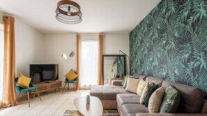 A modern living room with a sectional sofa, a TV, and a wooden coffee table. - Happy Stay Disneyland Paris - Garden Apartment + Parking (Montévrain)