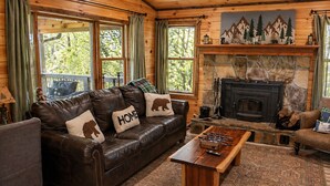 Ein gemütliches Blockhaus-Interieur mit Ledersofa, Kamin und einem Holztisch.
