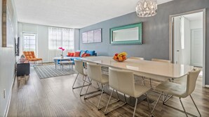 A modern dining area with a long table, chairs, and a chandelier. - Amazing Condo 3 min to the Beach (Sunny Isles Beach)