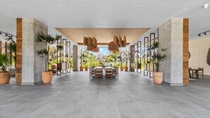 Een ruime lobby met een centraal gelegen eetgedeelte, grote potplanten en uitzicht op de skyline.