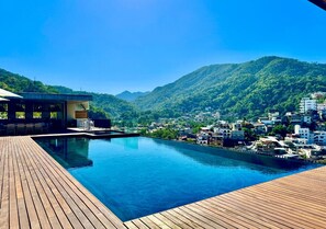 A modern pool area with a wooden deck, overlooking a mountainous landscape and a town. - Unique Incredible Oasis Vallarta - 2 Bed 2 bath! (Puerto Vallarta)