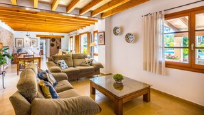 A spacious living room with wooden beams, a sofa set, a coffee table, and a dining area. - Beautiful house with views to the mountains near Pollensa (Pollensa / Pollença)