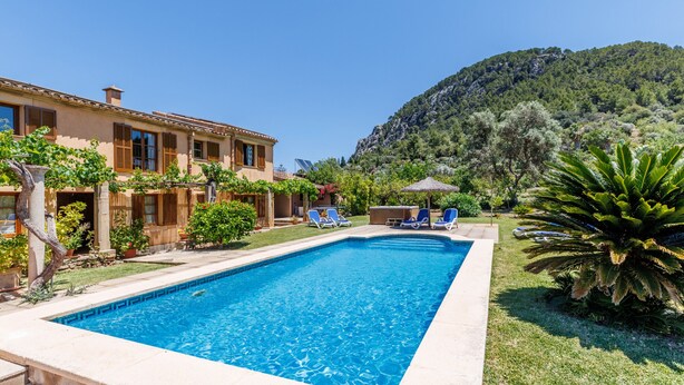 A swimming pool with lounge chairs, a building with a tiled roof, and a mountainous backdrop. - Beautiful house with views to the mountains near Pollensa (Pollensa / Pollença)