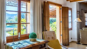 A room with a wooden table, a chair, a potted plant, and a view of greenery outside. - Beautiful house with views to the mountains near Pollensa (Pollensa / Pollença)