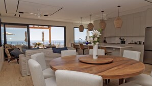 A modern kitchen with a round wooden table, white chairs, and a view of the ocean. - Exquisite oceanfront luxury casa, Pezula Beach (San Jose del Cabo)