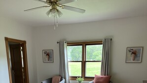 A bedroom with a bed, two chairs, a table, and a window with curtains.