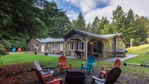 Una cabaña con un patio cubierto, mobiliario exterior y una chimenea.