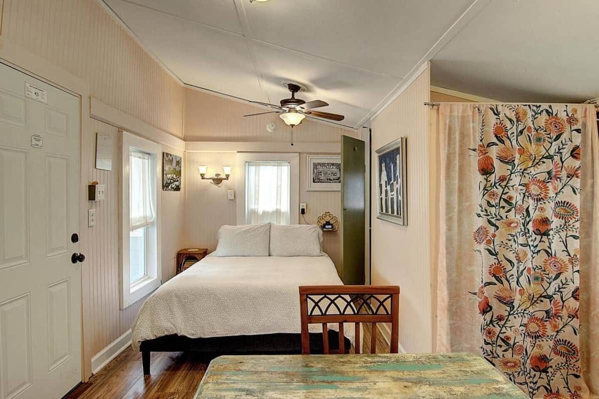 Ein Schlafzimmer mit einem Bett, einem Sessel, einem Deckenventilator und einem Fenster.
