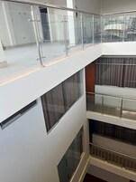 Interior de varios niveles con barandillas de vidrio y vista a un comedor inferior.