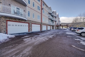 A multi-story building with a row of white garage doors, a covered parking area, and a clear sky.