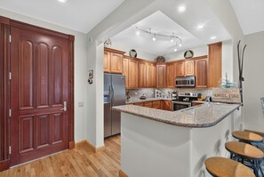 A modern kitchen with wooden cabinets, a central island, and a built-in oven.