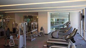 Een fitnessruimte met loopbanden, krachtapparaten en een spiegelwand.