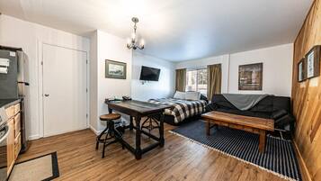 A compact room with a bed, a desk, a chair, a television, and a wooden wall.