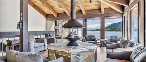 A cozy lounge area with stone-topped tables, grey upholstered sofas, and a wood-paneled ceiling.