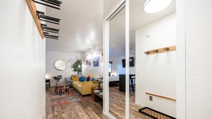 A modern living room with a wooden floor, a yellow sofa, a coffee table, and a mirror. - Striking Deluxe Studio w/Kitchen #114 at Donner Lake Village (Truckee)