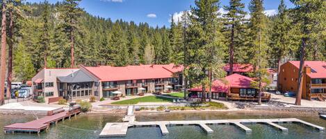 Un chalet avec un toit rouge, un quai et un lac entouré d’arbres.