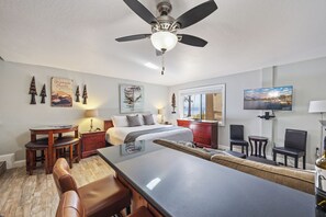 Una habitación de hotel con cama, escritorio, mesa de comedor y televisor.
