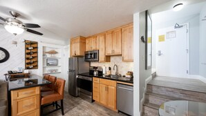 A modern kitchen with wooden cabinets, stainless steel appliances, and a glass dining table.