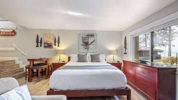 Une chambre à coucher comprenant un lit, des tables de chevet, une commode, une chaise et une fenêtre donnant sur un beau paysage.