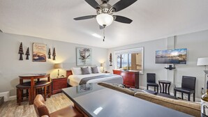 A hotel room with a bed, a desk, a dining table, and a TV.