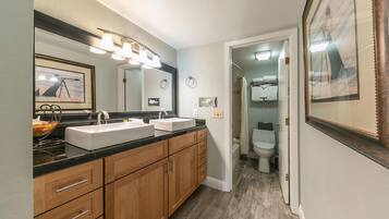 A modern bathroom with a double sink vanity, a large mirror, and a shower area.