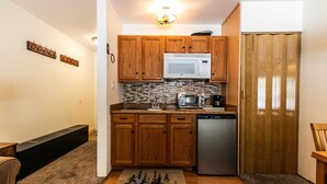 A compact kitchen with wooden cabinets, a microwave, a toaster, and a dishwasher. - Cozy Studio w/Kitchenette and Balcony #212 at Donner Lake Village (Truckee)