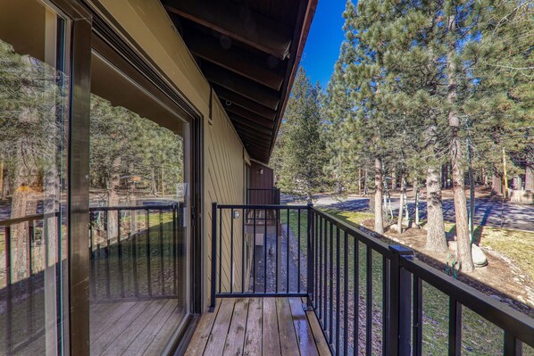 A wooden deck with a glass door leading to a covered porch.