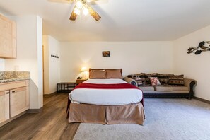 Une chambre à coucher comprenant un lit, une table de chevet, une lampe, un canapé et un ventilateur de plafond.