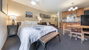 A hotel room with a bed, a desk, a chair, a bench, a kitchenette, and a ceiling fan. - Studio w/Kitchen 2nd Floor #217 at Donner Lake Village (Truckee)