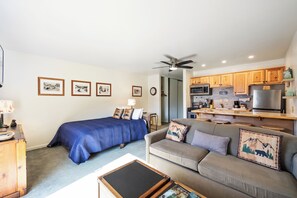 A compact living space with a bed, a sofa, a dining area, and a kitchenette.