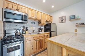 A kitchen with wooden cabinets, stainless steel appliances, a microwave, stove, and refrigerator. - Cozy Studio w/ Partial Lake view #223 at Donner Lake Village (Truckee)