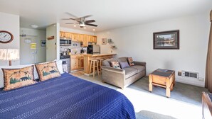 Een slaapkamer met een bed, een bureau, een kitchenette en een zithoek.
