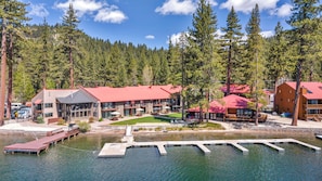 A lodge with a red roof, a dock, and a lake surrounded by trees.
