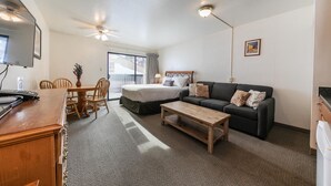 A hotel room with a bed, a sofa, a coffee table, a TV, and a desk with a computer. - Cozy Studio #226 at Donner Lake Village (Truckee)