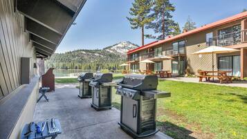 An outdoor patio area with barbecue grills, picnic tables, and a view of a mountain.
