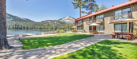 Un hôtel situé au bord d’un lac, doté d’une pelouse bien entretenue, de sièges extérieurs et offrant une vue sur le lac et les montagnes.