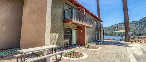 Un edificio moderno con un balcone, un tavolo da picnic e vista su un lago.