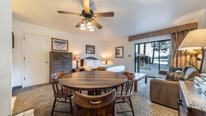 Une pièce chaleureuse avec une table à manger en bois, des chaises, un canapé et un ventilateur de plafond.