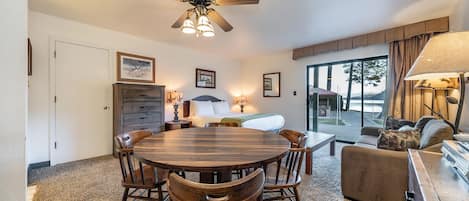 A cozy room with a wooden dining table, chairs, a sofa, and a ceiling fan.