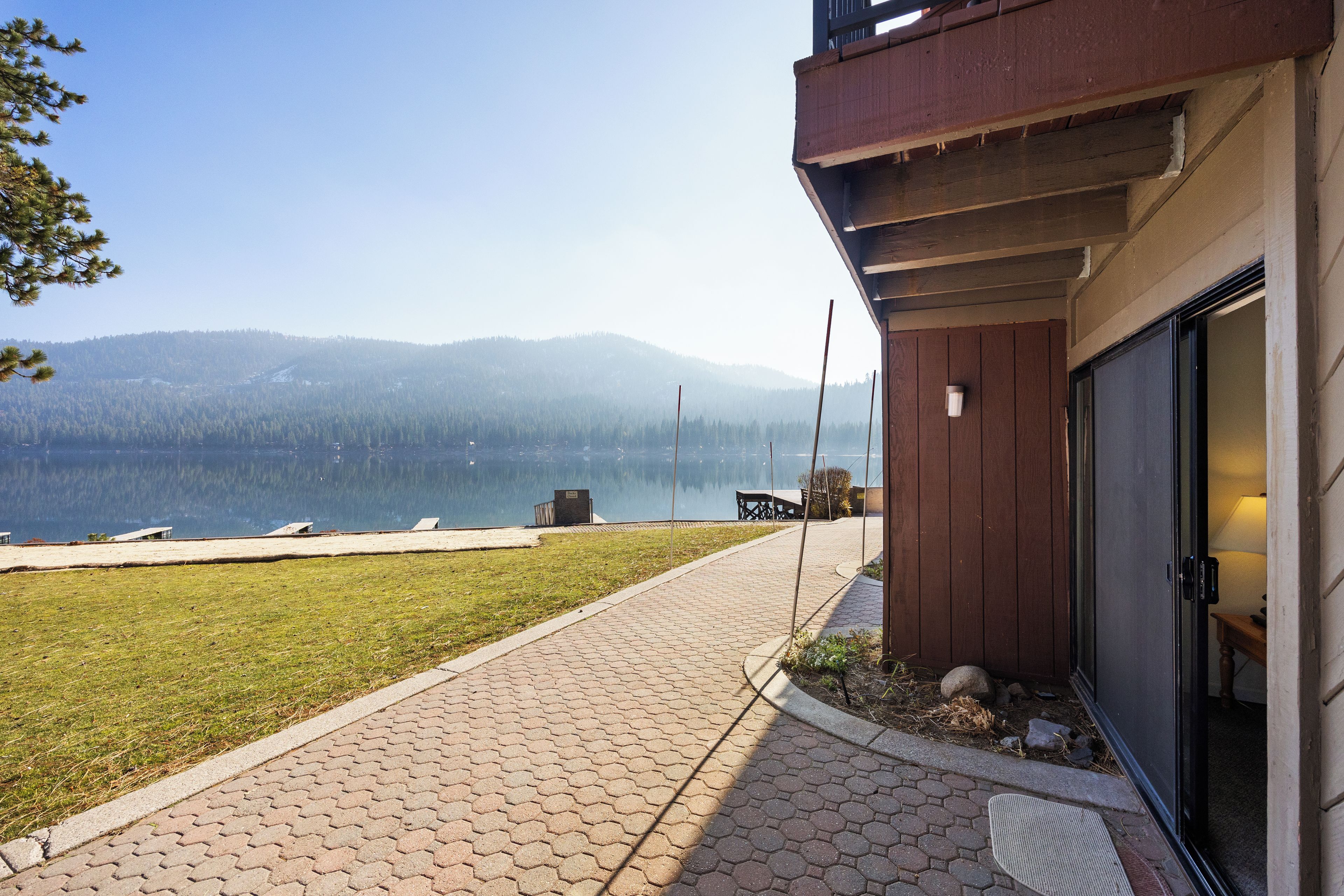 Un sentier menant à un bâtiment d’où l’on peut admirer un lac et des montagnes.