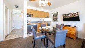 A compact kitchen with wooden cabinets, a microwave, and a dining area with a glass table and chairs. - King Studio w/Lake View #145 at Donner Lake Village (Truckee)