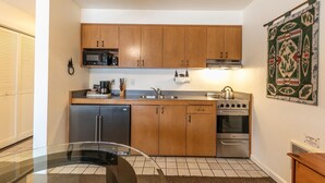 A compact kitchen with wooden cabinets, a stainless steel stove, a microwave, and a dishwasher. - King Studio w/Lake View #145 at Donner Lake Village (Truckee)