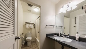 A bathroom with a toilet, sink, and shower. There are handrails and a towel rack.
