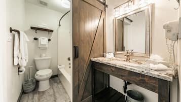 A bathroom with a wooden door, a marble sink, a mirror, and a toilet.
