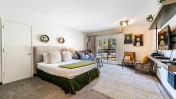 A bedroom with a bed, a sofa, a desk, and a balcony with a view.