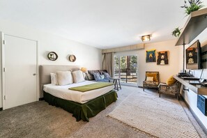 Une chambre avec un lit, un canapé, un bureau et un balcon offrant une vue.