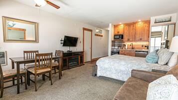 A compact living space with a kitchenette, a dining area, and a bedroom.