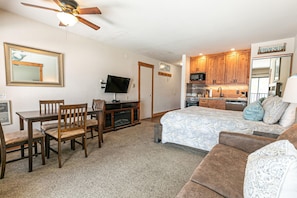 A compact living space with a kitchenette, a dining area, and a bedroom.