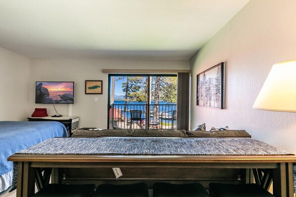 Habitación de hotel con cama, escritorio, silla, televisor y balcón con vista al mar.